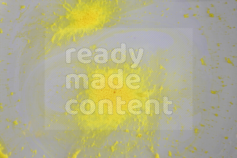 The image captures a dramatic splatter of yellow paint over a white backdrop