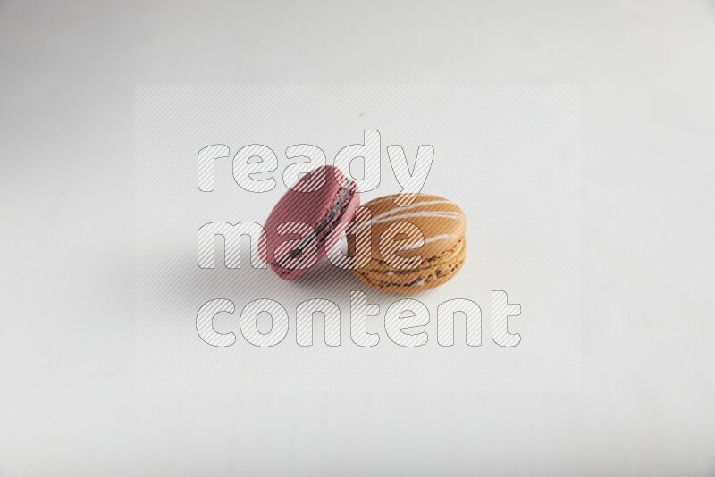 45º Shot of of two assorted Brown Irish Cream, and Red Cherry macarons on white background