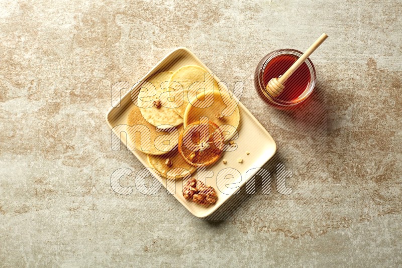 Five stacked dried orange mini pancakes in a rectangular plate on beige background