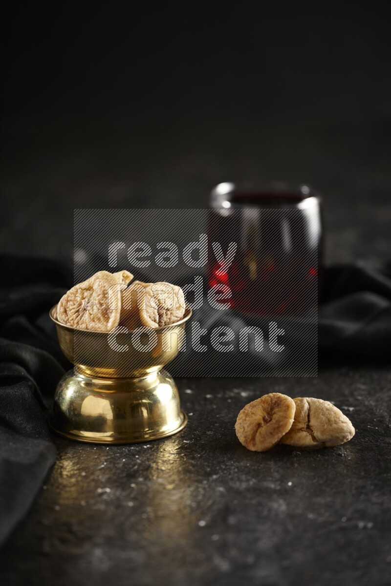 Dried fruits in a metal bowl with Hibiscus and a napkin in a dark setup