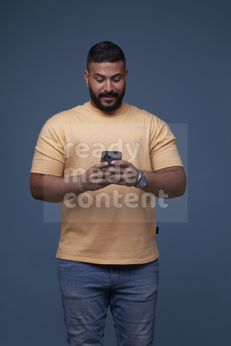 A man Texting on his phone in Blue Background wearing Orange T-shirt