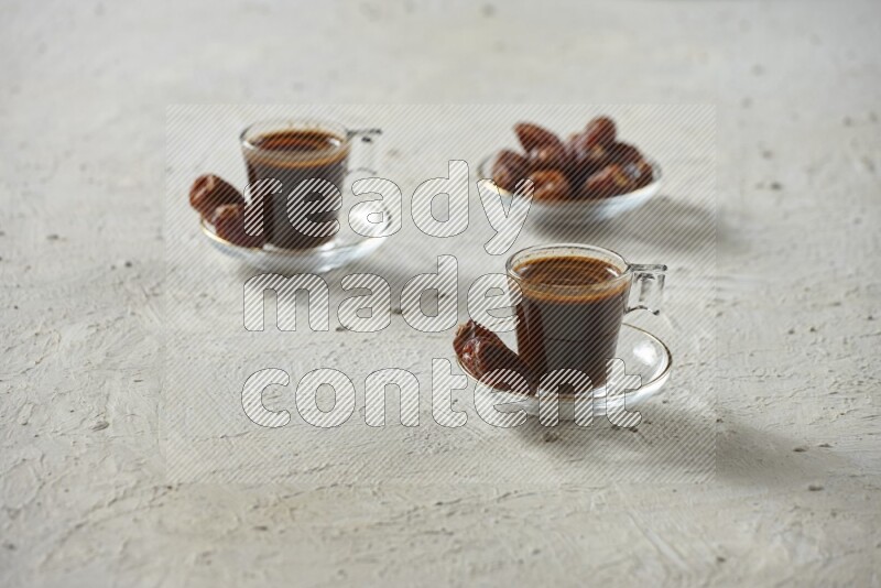 A coffee glass cup with dates and tea on textured white background