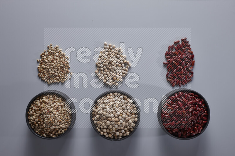 Legumes in pottery bowls on light grey background