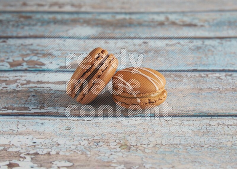 45º Shot of of two assorted Brown Irish Cream, and Brown Coffee macarons on light blue background