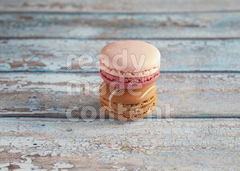 45º Shot of of two assorted Brown Irish Cream, and Pink Litchi Raspberry macarons on light blue background