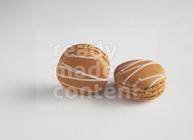 45º Shot of two Brown Irish Cream macarons on white background