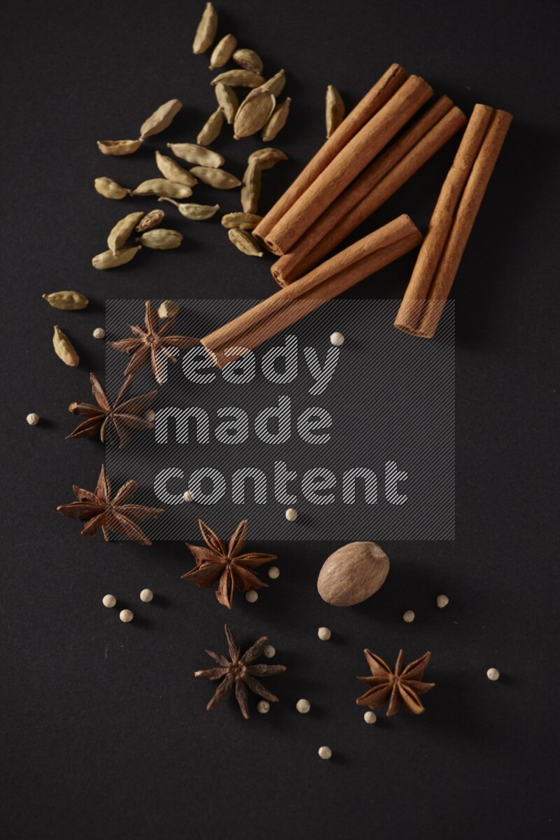 Cinnamon sticks, cardamom, star anise, nutmeg and white peppers on a black background
