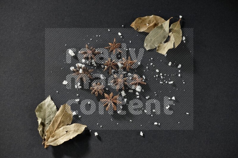 Salt, star anise and bay laurel on black flooring