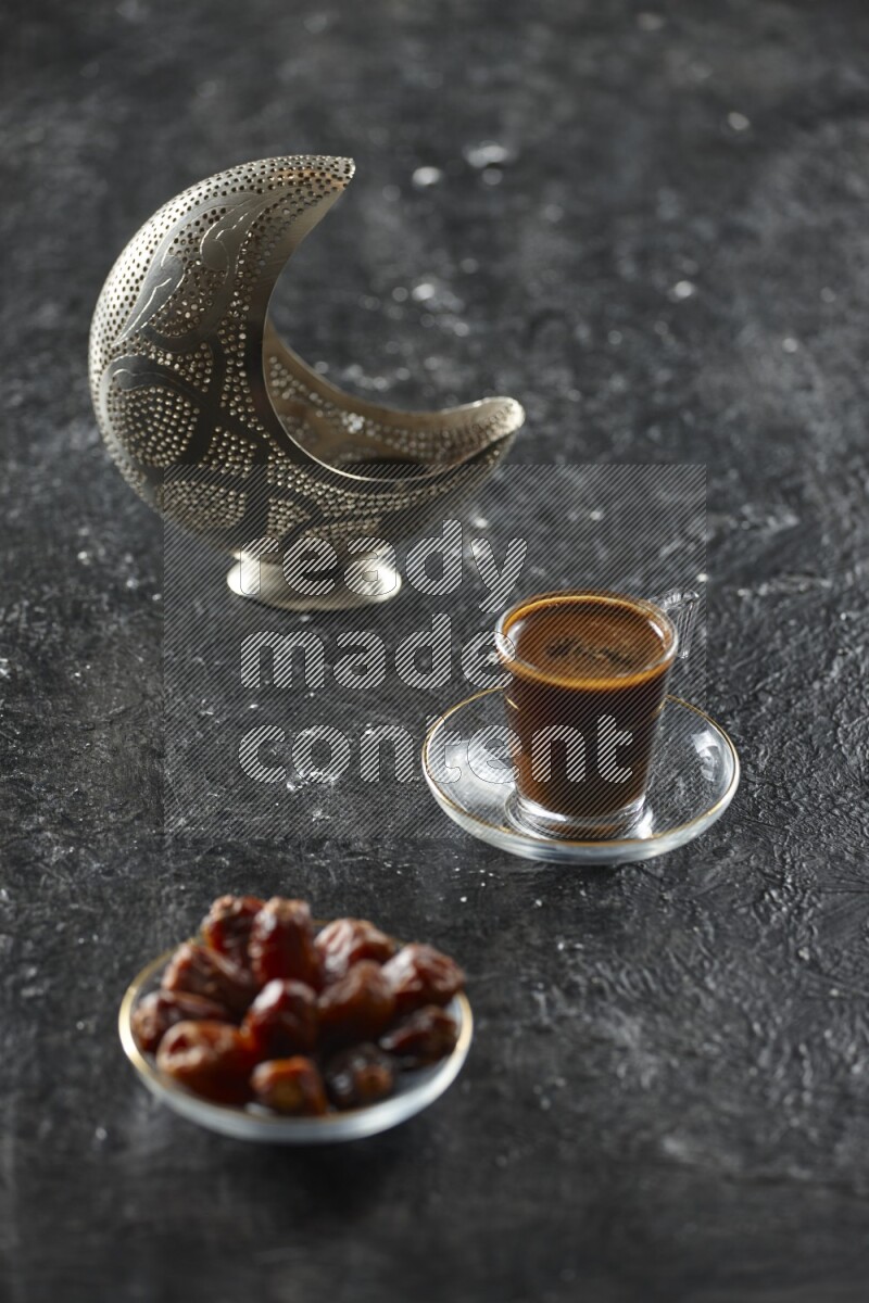 A silver lantern with different drinks, dates, nuts, prayer beads and quran on textured black background