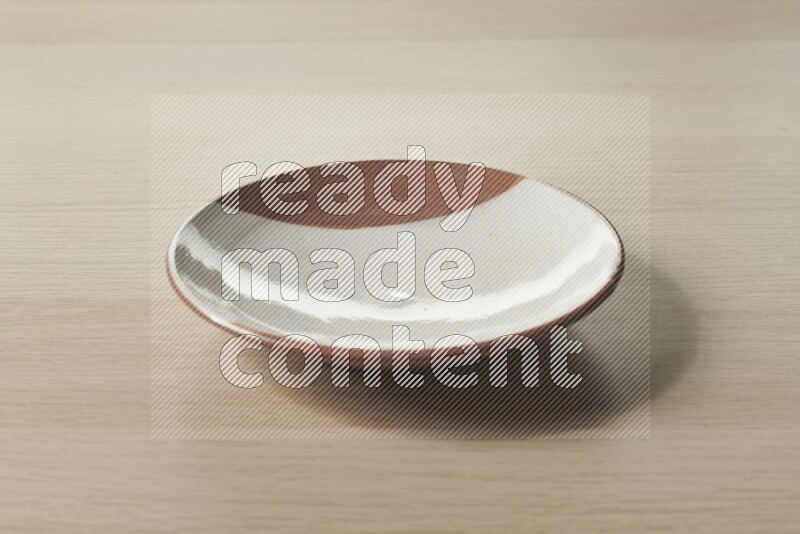 A multicolored pottery plate on light wooden background