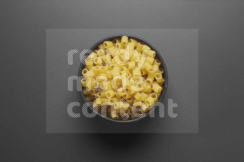 Big rings pasta in a pottery bowl on grey background