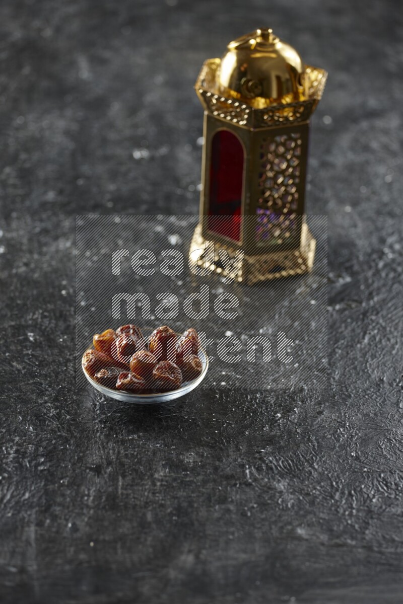 A golden lantern with different drinks, dates, nuts, prayer beads and quran on textured black background