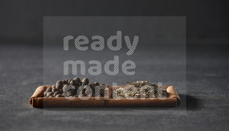 2 squares of cinnamon sticks full of cumin and allspice on black flooring