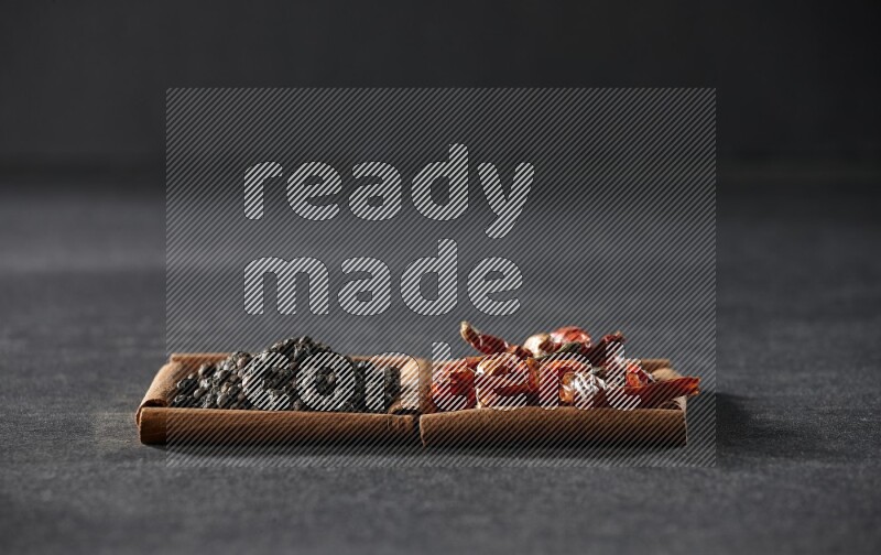 2 squares of cinnamon sticks full of chilis and black peppers on black flooring