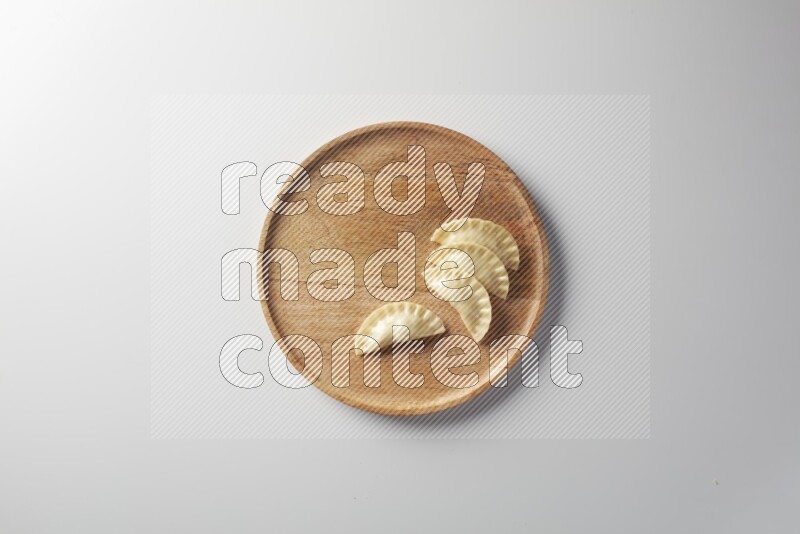 Four Sambosas on a wooden round plate on a white background
