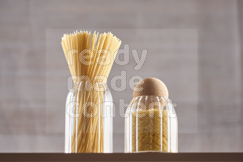 Raw pasta in glass jars on beige background