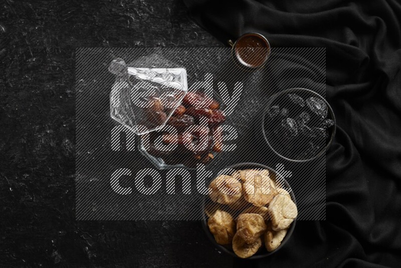 Dates in glass bowl with coffee and dried fruits in a dark setup