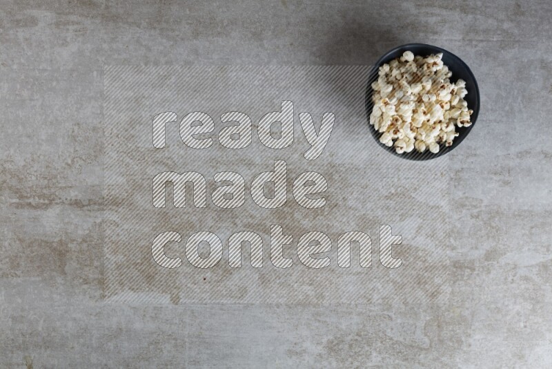 popcorn in black bowl on a grey textured countertop