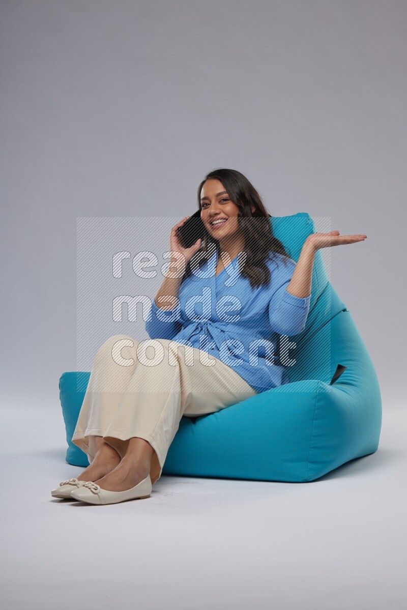 A woman sitting on a blue beanbag and talking on the phone