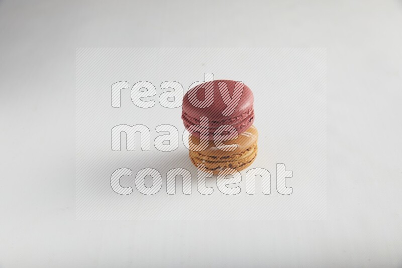 45º Shot of of two assorted Brown Irish Cream, and Red Velvet macarons on white background