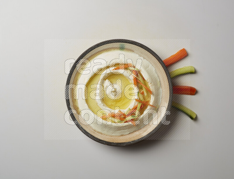 Lebnah garnished with sliced carrots &cucumber in a pottery plate on a white background