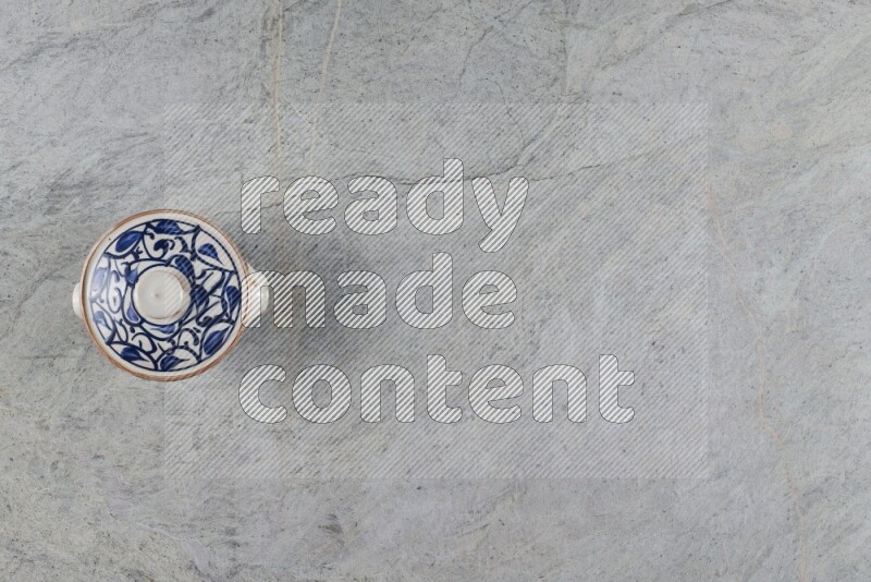 A multicolored pottery pot with its lid on grey marble background