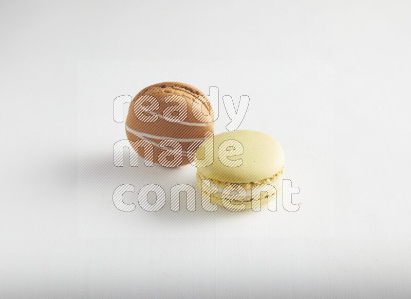 45º Shot of of two assorted Brown Irish Cream, and Yellow Lime macarons on white background