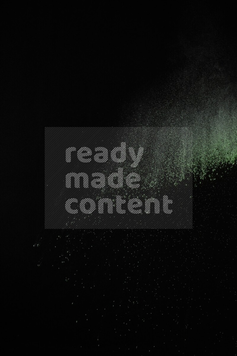 A side view of green powder explosion on black background
