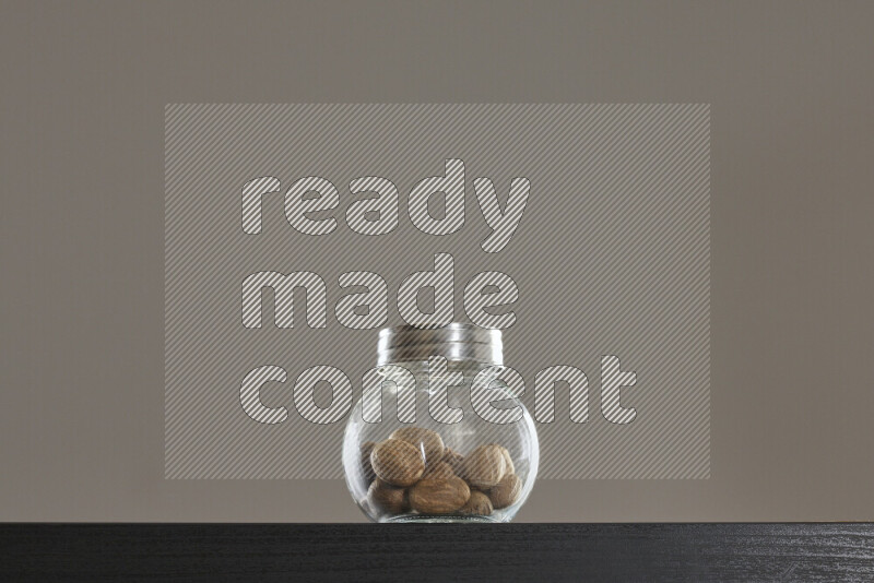 Nutmeg in a glass jar on black background