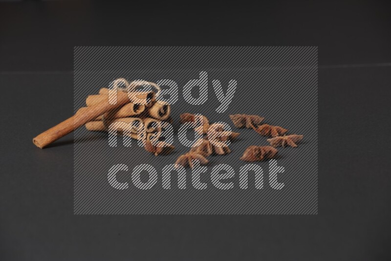 Cinnamon sticks stacked and bounded and star anise on black background