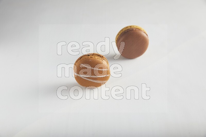 45º Shot of of two assorted Brown Irish Cream, and Yellow, and Brown Chai Latte macarons on white background