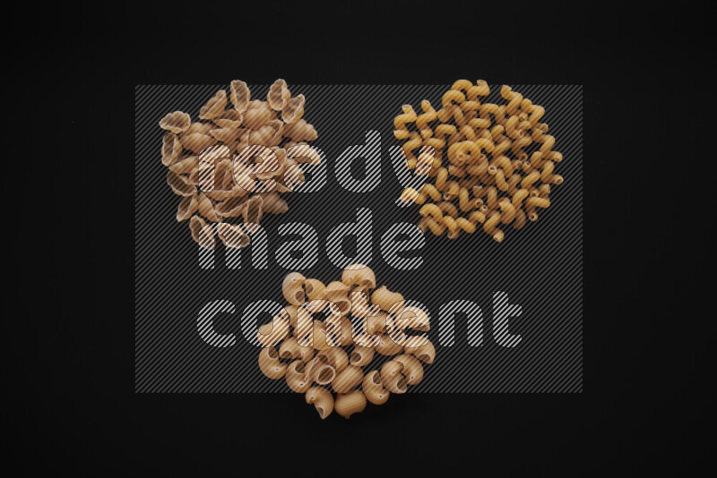 Different pasta types in bunches on black background