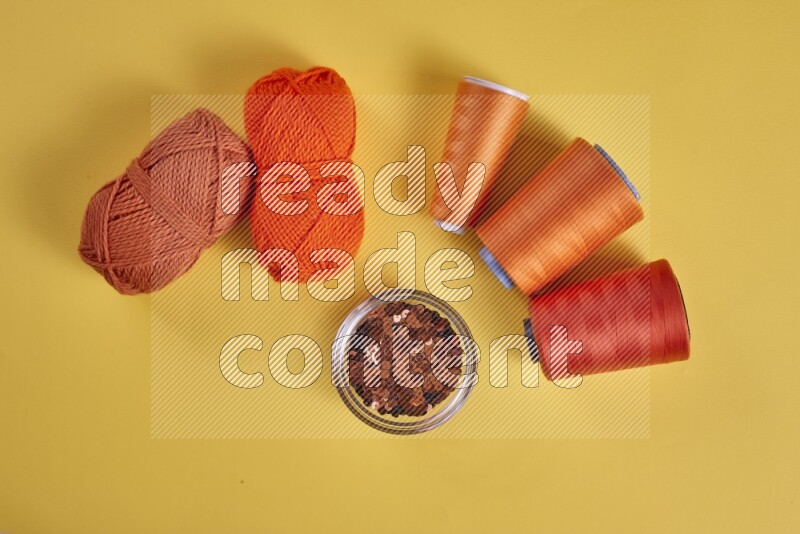 An orange collection of sewing and tailoring tools arranged on a yellow background