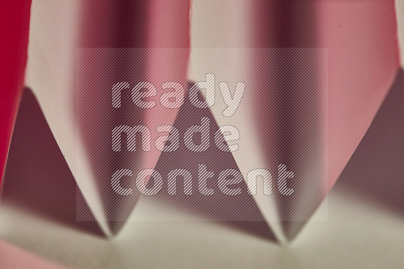 A close-up abstract image showing sharp geometric paper folds in white and red gradients