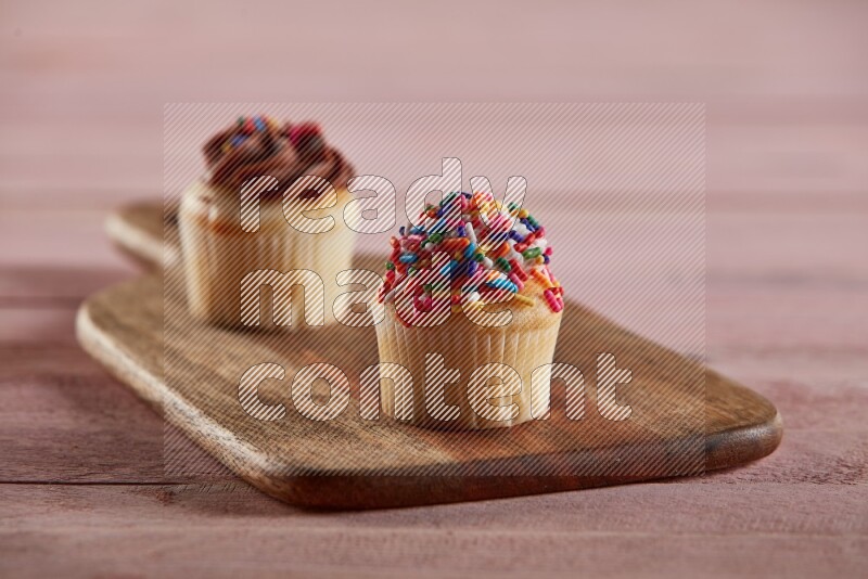 Vanilla mini cupcake topped with sprinkles on a wooden board
