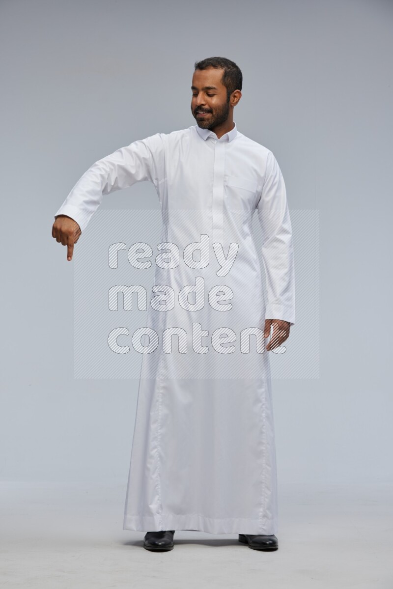 Saudi man Wearing Thob standing interacting with the camera on Gray background