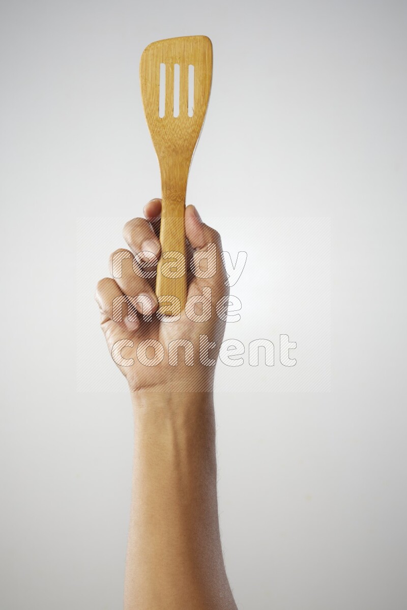 Male Hand Holding Slotted Turner on white background