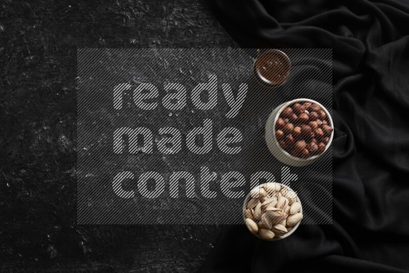 Nuts in pottery bowls with coffee in a dark setup