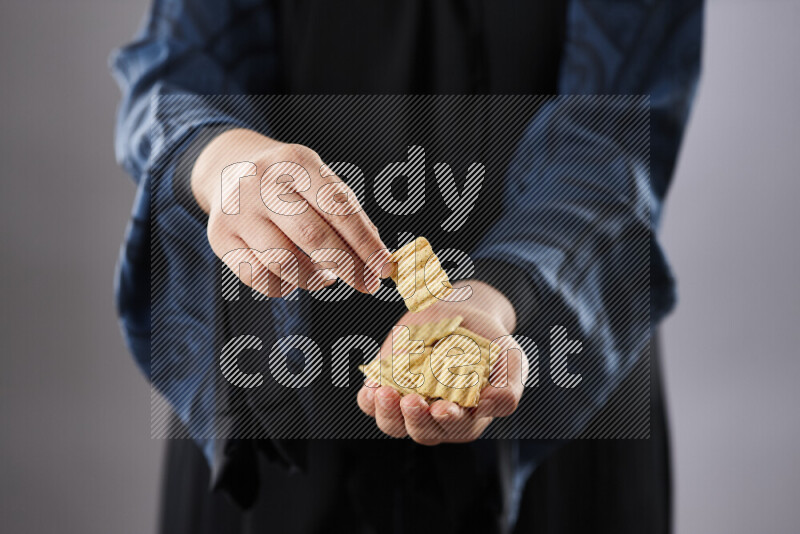 Woman in abaya holding different kinds of snacks in different positions
