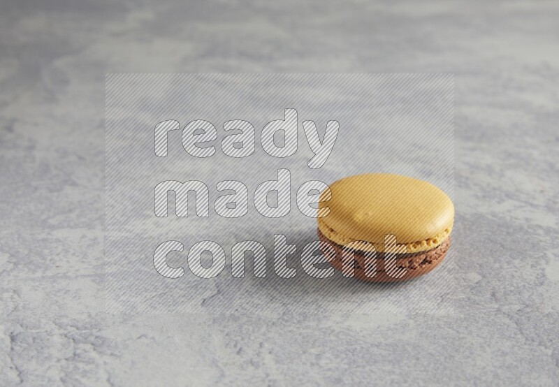 45º Shot of Yellow and Brown Chai Latte macaron on white  marble background
