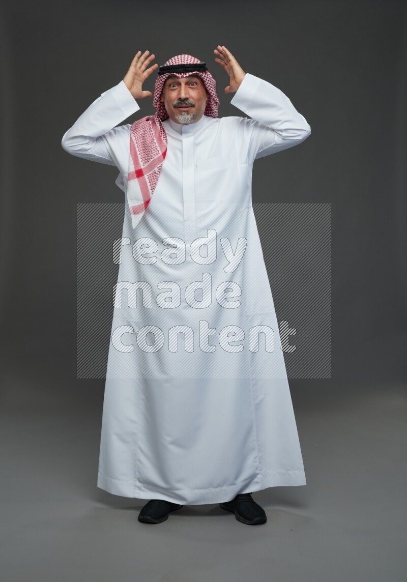 Saudi man with shomag Standing Interacting with the camera on gray background
