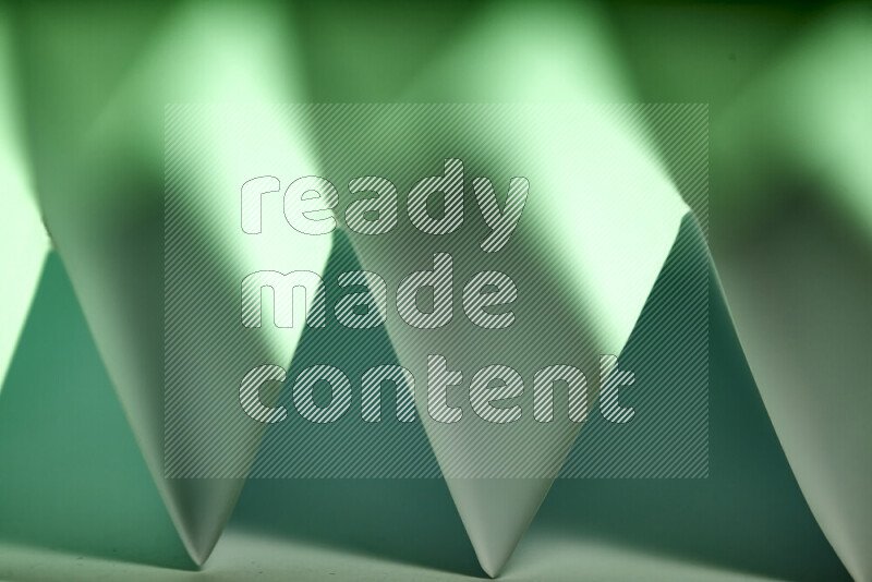 A close-up abstract image showing sharp geometric paper folds in green gradients