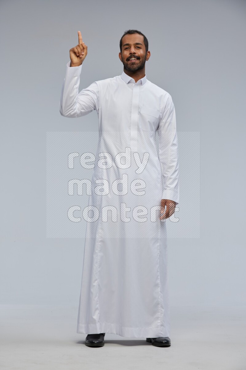Saudi man Wearing Thob standing interacting with the camera on Gray background
