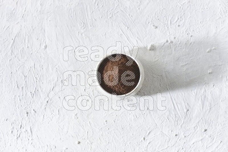 وعاء بيج من السيراميك ممتلئ ببودرة القرنفل علي خلفية بيضاء