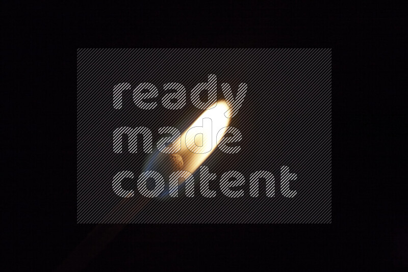 A burning matchstick isolated on dark backdrop