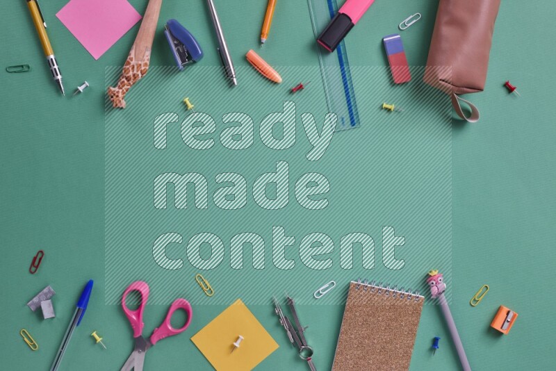 Different school supplies on green background