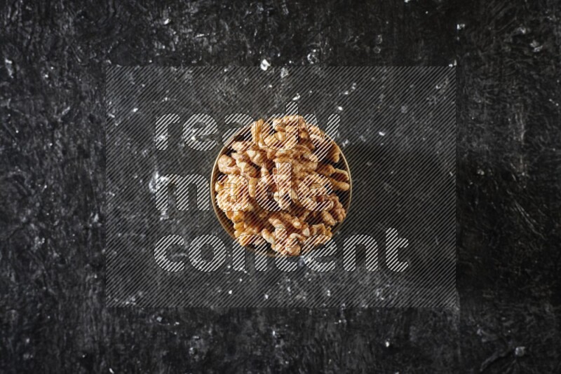 Nuts in a metal bowl in a dark setup
