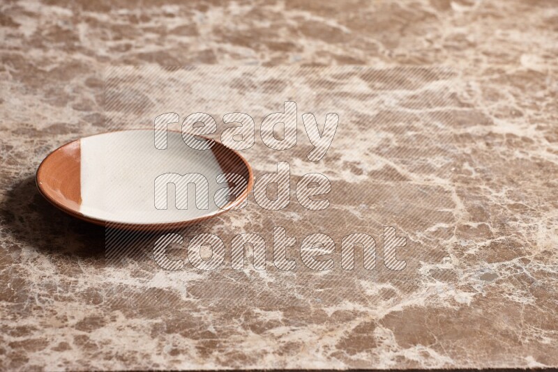 A multicolored pottery plate on beige marble background