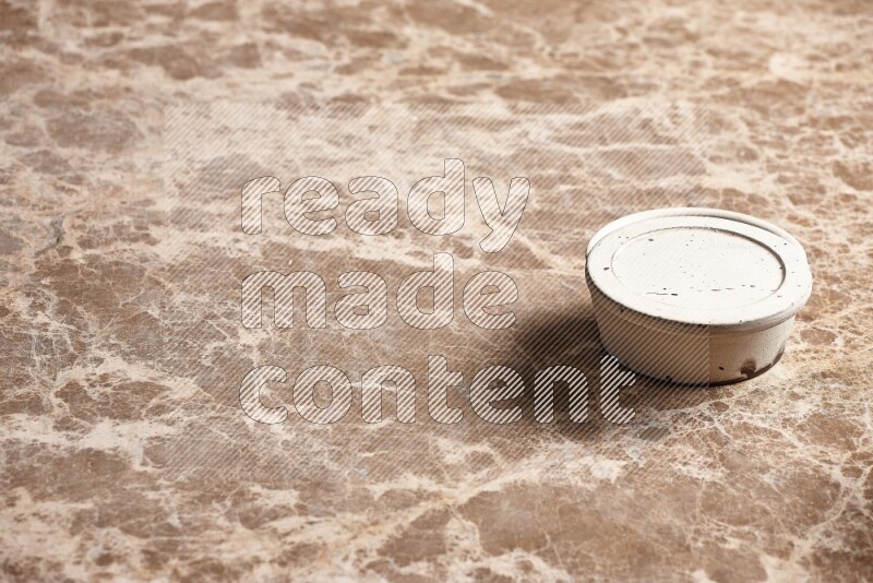 A white pottery bowl on beige marble background