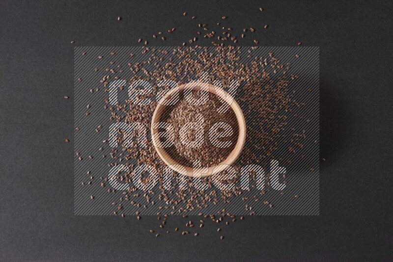 A wooden bowl full of flax surrounded by the seeds on a black flooring in different angles